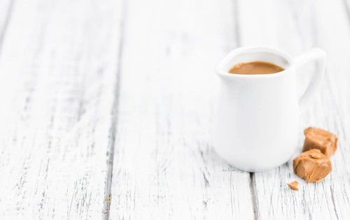 Caramel Sauce on an old wooden table as detailed close-up shot (selective focus)