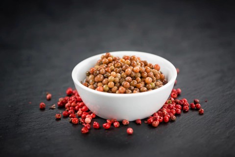 Some preserved Pink Peppercorns on a vintage slate slab, selective focus