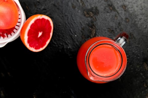 Some freshly squeezed Grapefruit Juice on a vintage background (close-up shot, selective focus)