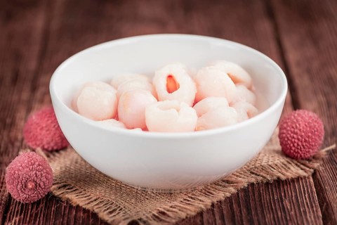 Lychees (preserved) as high detailed close-up shot on a vintage wooden table (selective focus)
