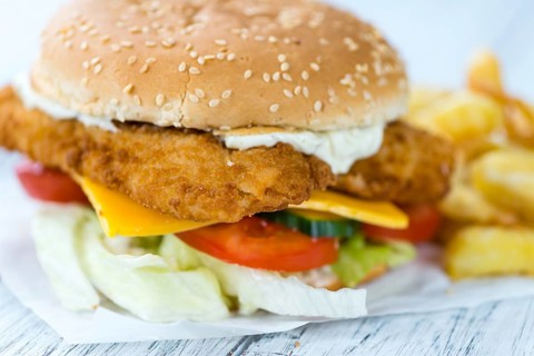 Wooden table with a fresh made Fish Burger (close-up shot, selective focus)