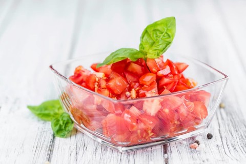 Tomatoes (diced) as high detailed close-up shot on a vintage wooden table (selective focus)