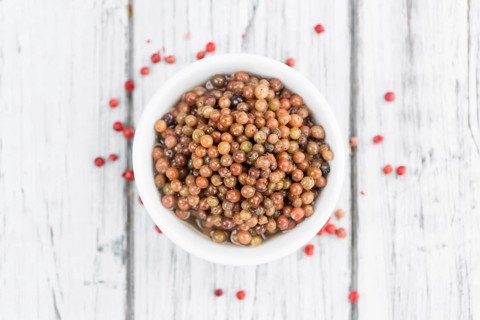 Preserved Pink Peppercorns on a vintage background as detailed close-up shot, selective focus
