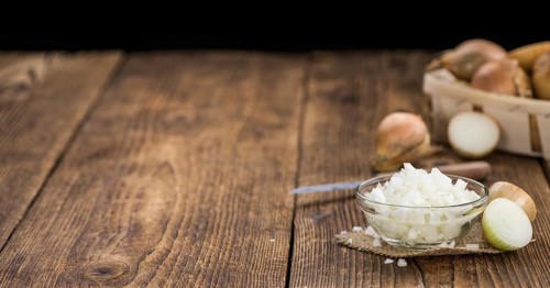 White Onions (dices) as high detailed close-up shot on a vintage wooden table, selective focus