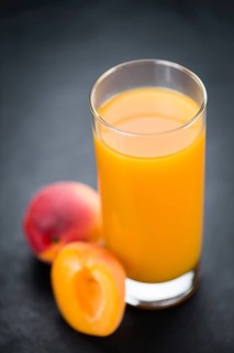 Fresh made Apricot Juice on a vintage background (close-up shot)