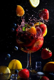 Sparkling sangria in a glass, surrounded by fruit and berries