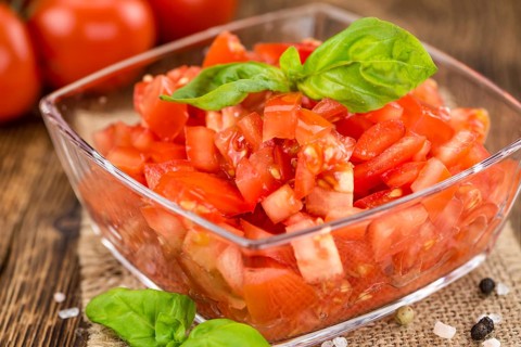 Tomatoes (diced) as high detailed close-up shot on a vintage wooden table (selective focus)