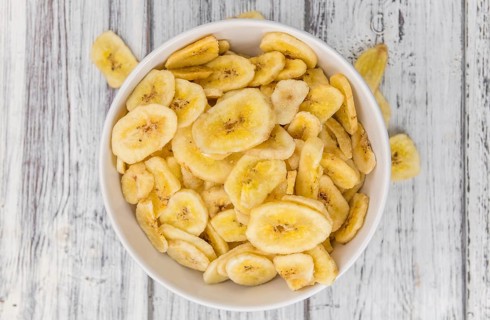 Homemade Dried Banana Chips on an wooden table as detailed close-up shot, selective focus