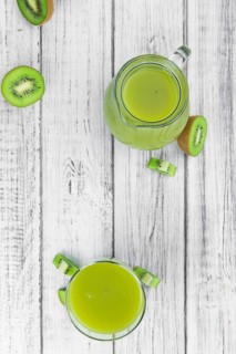 Wooden table with fresh made Kiwi Smoothie (close-up shot, selective focus)