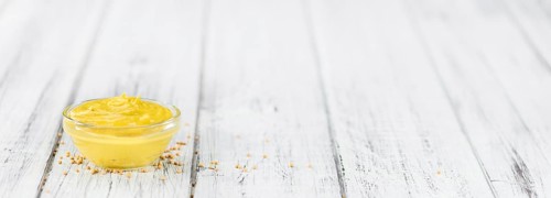 Mustard as high detailed close-up shot on a vintage wooden table (selective focus)