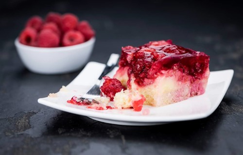 Fresh made portion of Raspberry Cake (selective focus, close-up shot) on rustic background