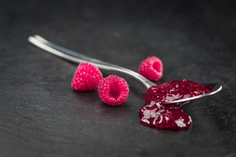 Portion of Raspberry Jam on a rustic slate slab, selective focus, close-up shot
