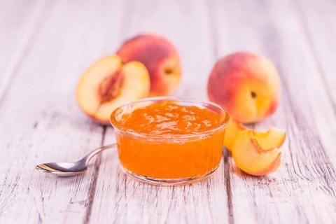 Peach Jam on an old wooden table as detailed close-up shot, selective focus