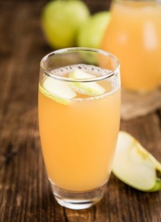 Homemade Apple Juice on an wooden table (selective focus) as detailed close-up shot