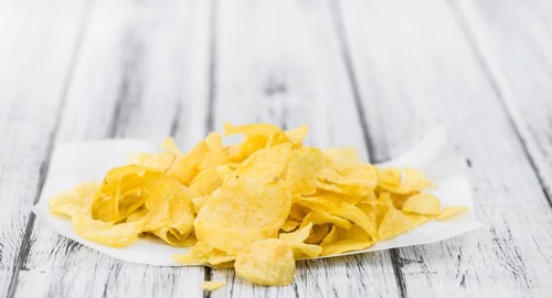 Cheese and Onion Potato Chips on a vintage background as detailed close-up shot (selective focus)