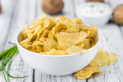 Potato Chips with Sour Cream taste as high detailed close-up shot on a vintage wooden table