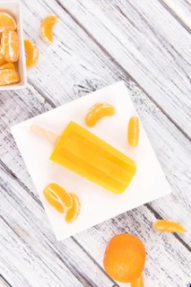 Portion of fresh homemade Tangerine Popsicles (close-up shot, selective focus) on a vintage