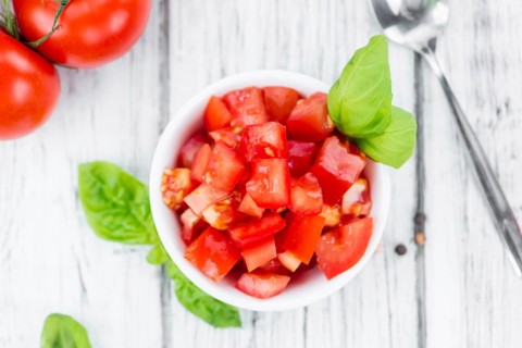 Tomatoes (diced) as high detailed close-up shot on a vintage wooden table (selective focus)
