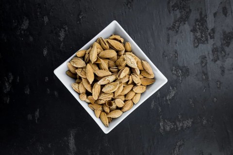 Almonds in shell (roasted and salted) on a vintage background (close-up shot)