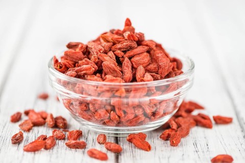 Goji Berries (dried) on an old wooden table as detailed close-up shot (selective focus)