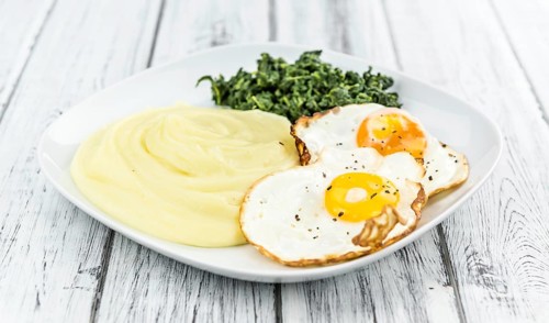 Some homemade Mash (selective focus) as detailed close-up shotwith fried eggs and spinach