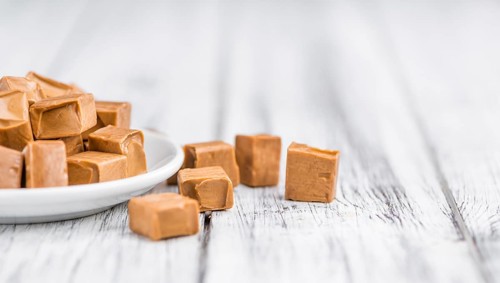 Caramel pieces as high detailed close-up shot on a vintage wooden table (selective focus)
