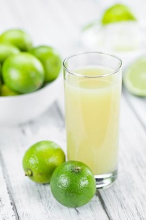 Fresh Lime Juice as high detailed close-up shot on a vintage wooden table (selective focus)