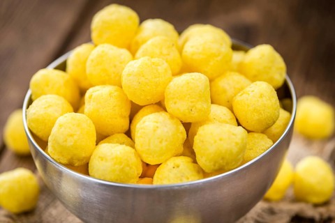 Cheese Balls (fried) as high detailed close-up shot on a vintage wooden table (selective focus)