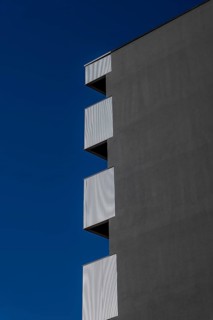 Beautiful Modern Concrete Design Building with Metal Balcony Against Blue Clear Sky in Switzerland