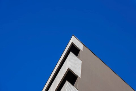 Beautiful Modern Concrete Design Building with Metal Balcony Against Blue Clear Sky in Switzerland