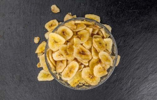 Portion of Dried Banana Chips on a rustic slate slab, selective focus, close-up shot