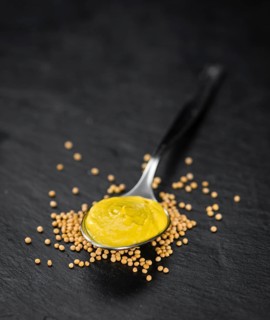 Fresh made Mustard on a vintage background (close-up shot)
