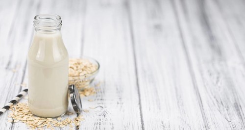 Healthy Oat Milk on a wooden table as detailed close-up shot (selective focus)