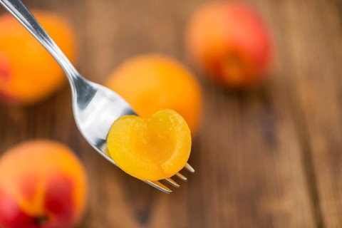 Canned Apricots on rustic wooden background (close-up shot)