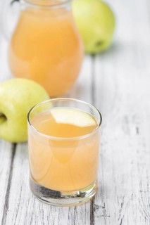 Homemade Apple Juice on an wooden table (selective focus) as detailed close-up shot