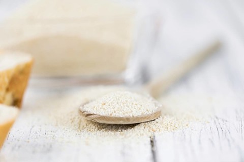 Wooden spoon with Breadcrumbs (close-up shot, selective focus) on an old wooden table