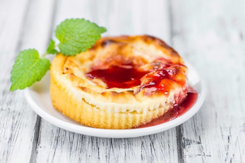 Fresh made Mini Cheesecake (with Sauce) on a vintage background (close-up shot)