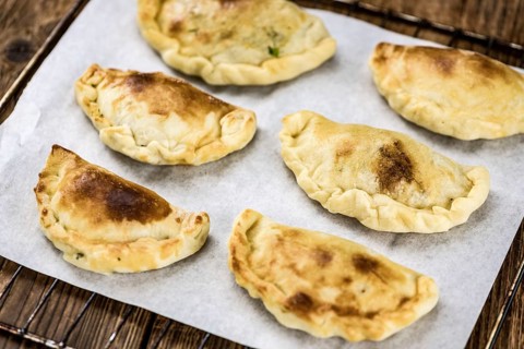 Portion of healthy Empanadas on an old wooden table (selective focus, close-up shot)