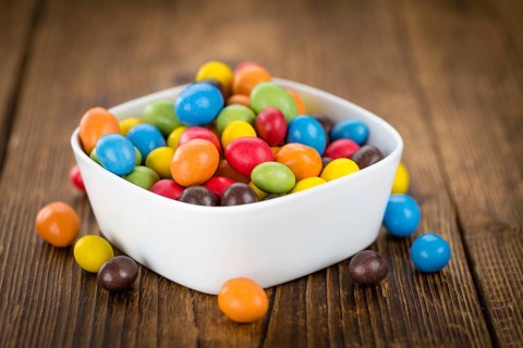 Cocolate coated Peanuts on rustic wooden background (close-up shot)