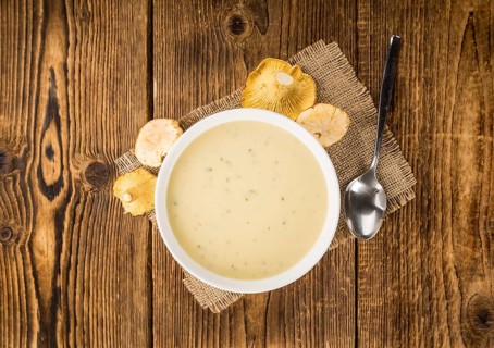 Chanterelle Soup as high detailed close-up shot on a vintage wooden table, selective focus