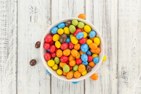Cocolate coated Peanuts on rustic wooden background (close-up shot)