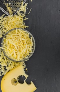 Homemade Grated Cheese (close-up shot) on a vintage slate slab