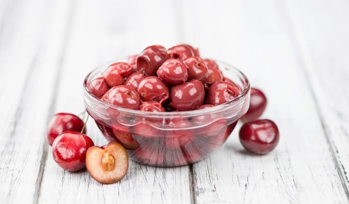 Canned Cherries as high detailed close-up shot on a vintage wooden table, selective focus