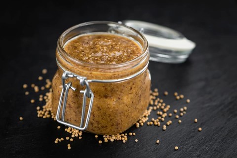 Portion of Mustard (sweet) as detailed close up shot on a slate slab (selective focus)