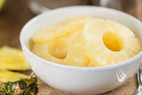 Preserved Pineapple Rings on an old wooden table as detailed close-up shot, selective focus