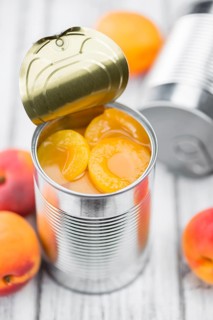 Canned Apricots on an old wooden table as detailed close-up shot (selective focus)