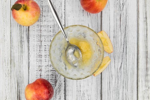 Portion of fresh made Applesauce (selective focus) on a wooden table