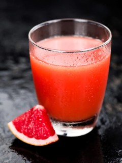Some freshly squeezed Grapefruit Juice on a vintage background (close-up shot, selective focus)