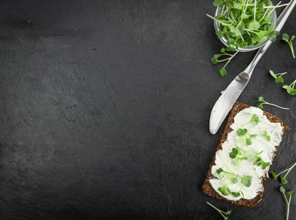 Fresh cutted Cress with creamy Cheese on a slice of bread (selective focus, close-up shot)
