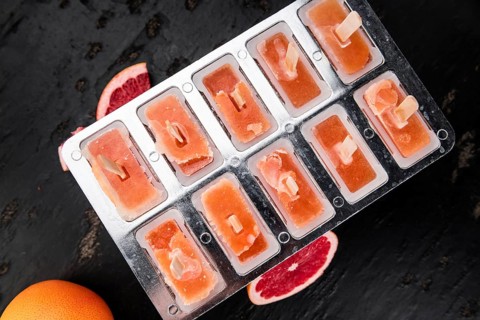 Some homemade Grapefruit Popsicles (with some fresh fruits) as close-up shot (selective focus)